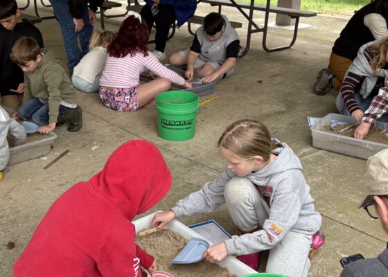 Kids digging through boxes of sand on the ground