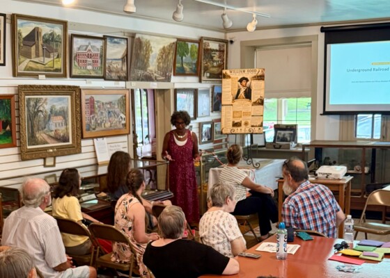 Woman standing amongst a crowd referencing a powerpoint presentation